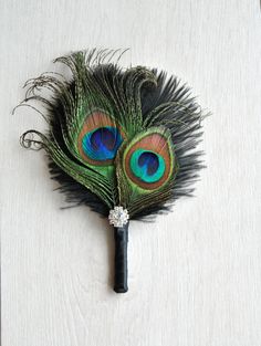 a peacock feather fan on a white surface with some feathers sticking out of it's side