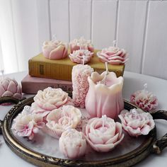 a tray with candles and flowers on top of it next to a stack of books