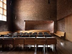 an empty room with rows of benches and tables in front of a brick wall,