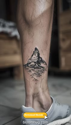 a man's foot with a mountain tattoo on it