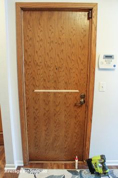 a wooden door in a white room with tools on the floor and an air conditioner next to it