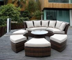 an outdoor furniture set on a deck in front of a large wooden structure with white cushions