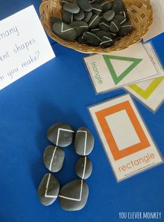 some rocks and paper on a blue table with a basket full of stones next to it