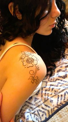 a woman laying on top of a bed with a tattoo on her arm and shoulder