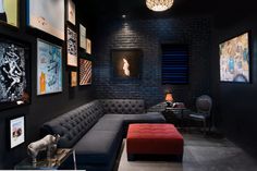 a living room with black walls and pictures on the wall, couches and tables