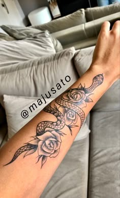 a woman's arm with a snake and rose tattoo on the left side of her arm