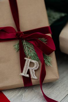 a christmas present wrapped in brown paper with a red ribbon and letter r on it