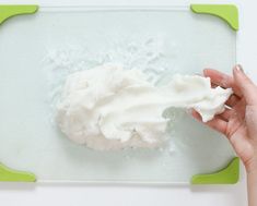 someone is spreading icing on top of some cake mix in a green tray with white frosting