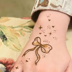 a woman's hand with a tattoo on it that has a bow and stars