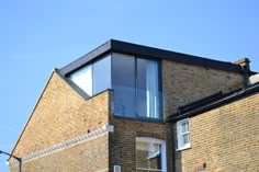 a tall brick building with a black roof and windows on it's side against a blue sky