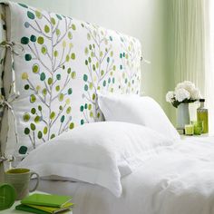 a bed with white linens and green wallpaper in a room that is well decorated