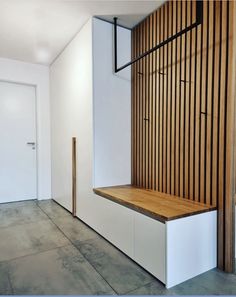 an empty room with a wooden bench and white walls