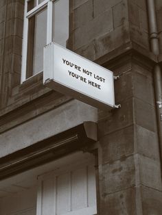 a sign on the side of a building that says you're not lost you're here