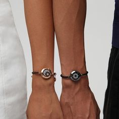 two people standing next to each other wearing bracelets