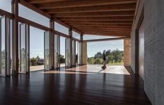 an empty room with lots of windows and wood flooring on the outside wall, along with a skateboarder in the middle