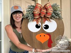 a woman holding up a wooden turkey sign