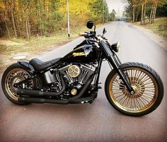 a black and gold motorcycle parked on the side of a road in front of trees