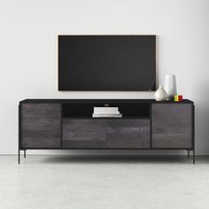 an entertainment center with a large television mounted on it's sideboard, in front of a white wall