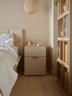 a bed room with a neatly made bed next to a book shelf and a night stand