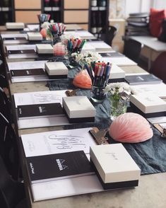 the long table is set up with many books and pencils in vases on it