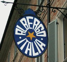 a blue and white sign hanging from the side of a building