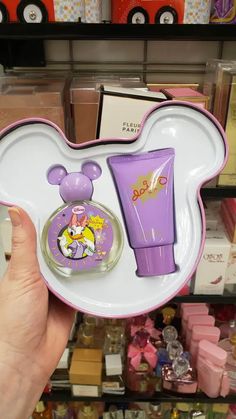 a person holding up a purple and white mickey mouse gift set in front of a store shelf