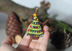 a hand holding a tiny beaded christmas tree ornament