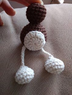 a crocheted doll is being held up by someone's hand on a couch