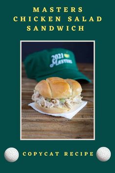 a chicken salad sandwich sitting on top of a wooden table next to a green hat