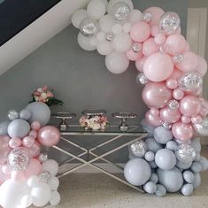 balloons are arranged in the shape of an arch on a table with silver and pink decorations