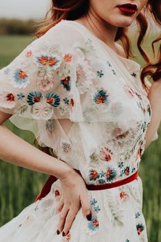 a woman with red hair wearing a white dress and holding her hands on her hips