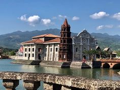 an old building next to a body of water with mountains in the background