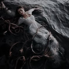 a woman laying on top of a rope in the ocean next to a body of water