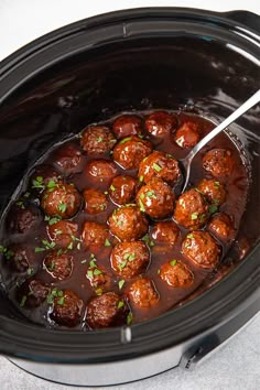 a crock pot filled with meatballs and gravy on top of a table