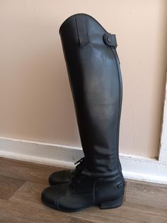 a pair of black boots sitting on top of a wooden floor next to a wall