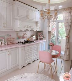 a kitchen with white cabinets and pink chairs