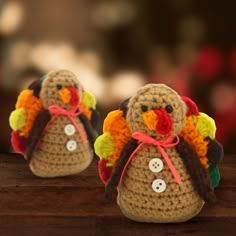 two small crocheted turkeys sitting on top of a wooden table next to each other