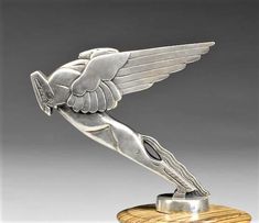 a silver statue with wings on top of a wooden stand