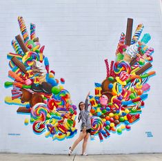 a woman standing in front of a wall painted with candy and candies on it