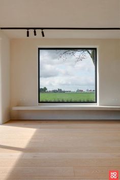 an empty room with a large window and wooden floor