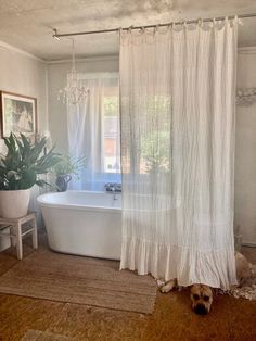 a white bath tub sitting next to a shower curtain in a bathroom with a rug on the floor