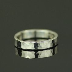 a close up view of a silver ring on a black surface with the reflection of it