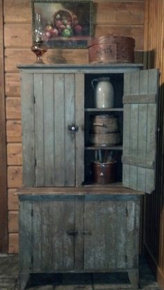 an old wooden cabinet with pots and pans on it in a room that has wood paneling