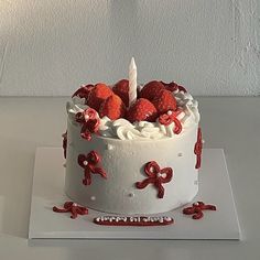 a white cake topped with strawberries and a candle