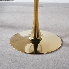 a gold table with a black base on carpeted floor next to wall and window