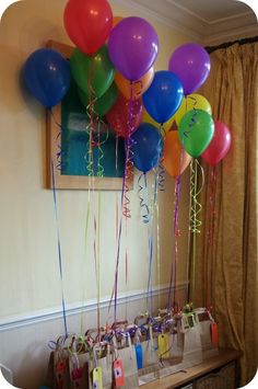 a bunch of balloons that are hanging from a string on a wall in a room