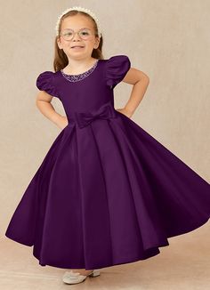 Have your flower girl dressed to impress your friends and family while she wears our matte satin little ballgown, Jewel. Her neckline is jeweled with hand sewn beading, puff sleeves, and a beautiful bow belt that sits atop a full box-pleat tea length skirt. We have matching pearls at the sleeves and a removable back bow. Dark Purple Gown, Satin Flower Girl Dresses, Grape Flower, Purple Flower Girls, Tea Length Flower Girl Dress, Dark Purple Dresses, Frocks For Kids, Purple Girls Dress, Dark Purple Flowers