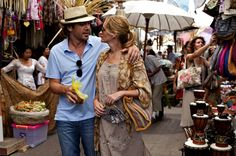 a man and woman walking through an outdoor market