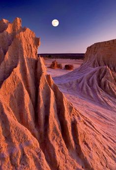 the moon is setting over some desert formations