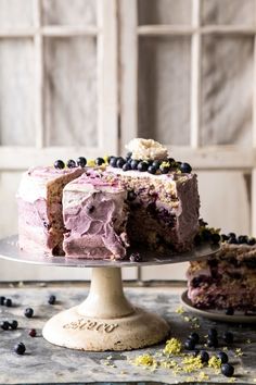 there is a cake with purple frosting and blueberries on it